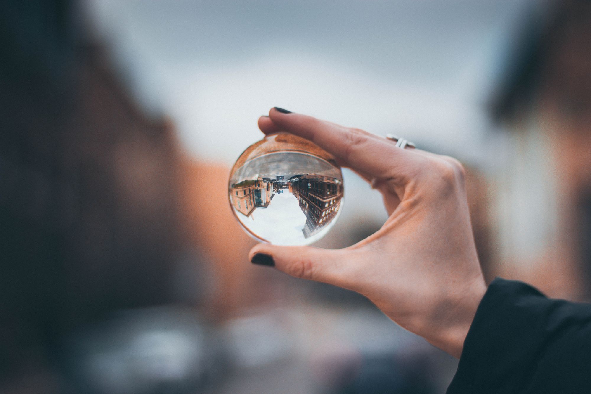 Woman's hand holding a crystal ball which is reflecting some buildings