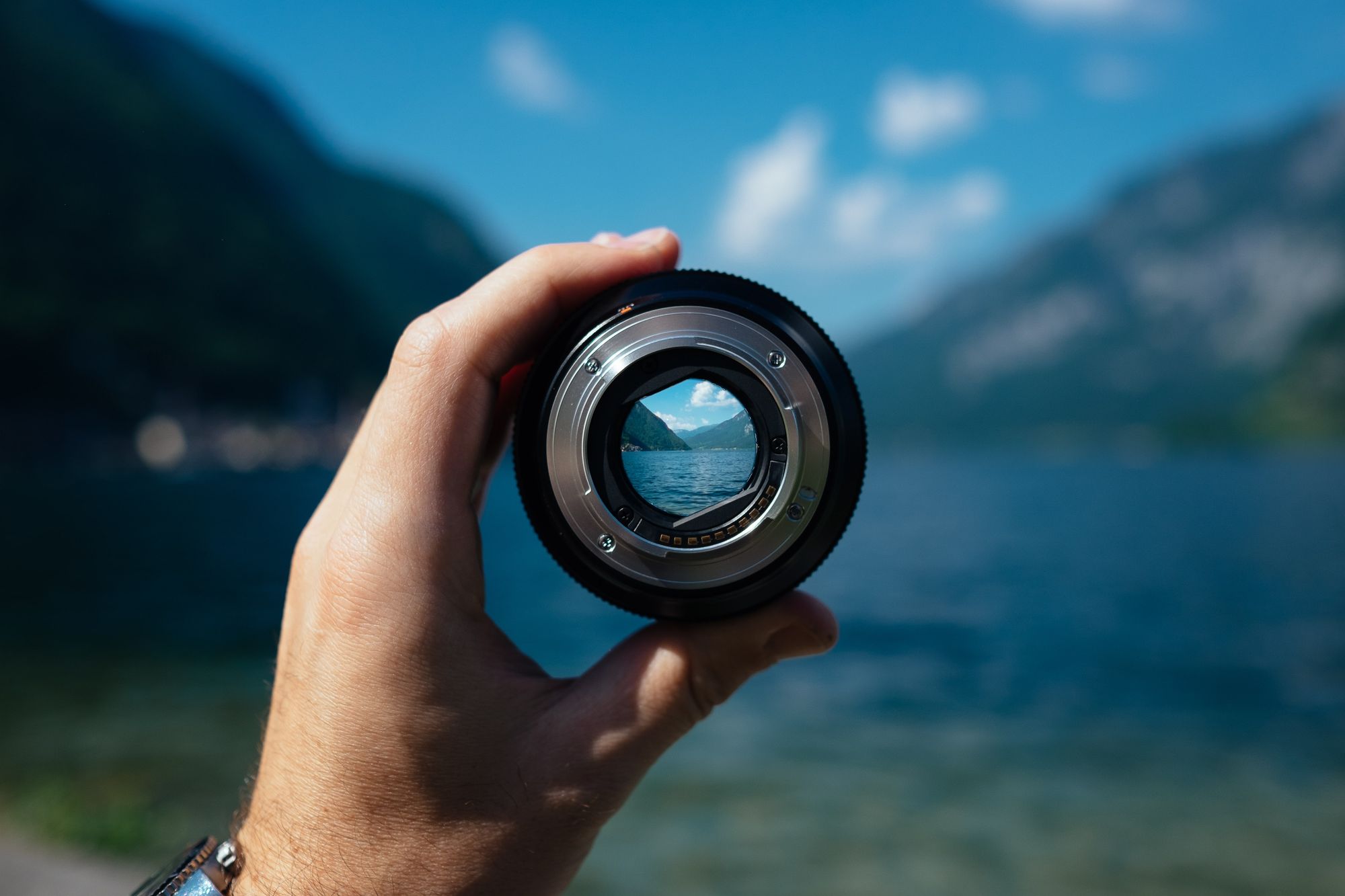 Hand holding a lens in front of a view of a fjord