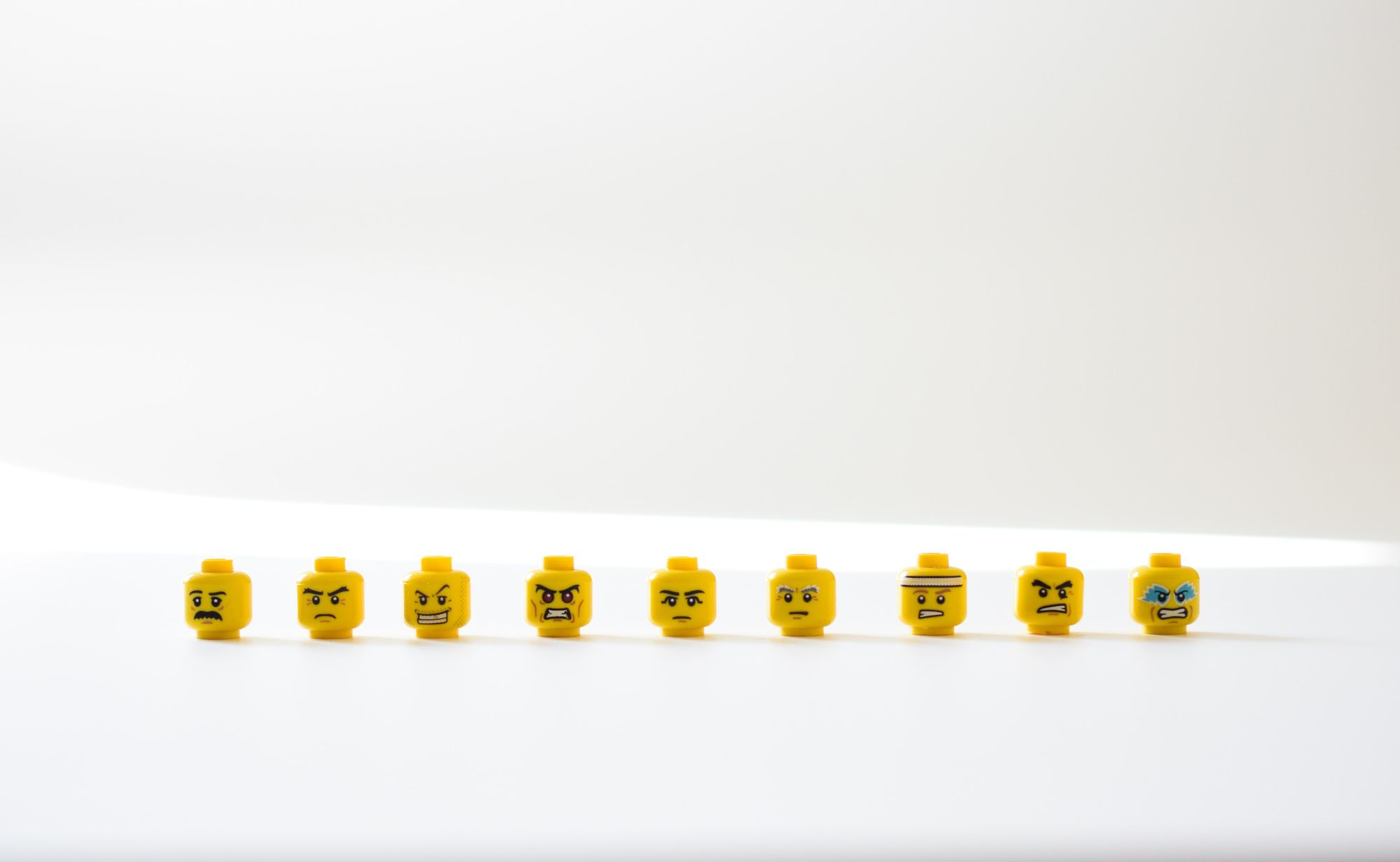 Image of lego heads in a line each with a slightly different angry expression
